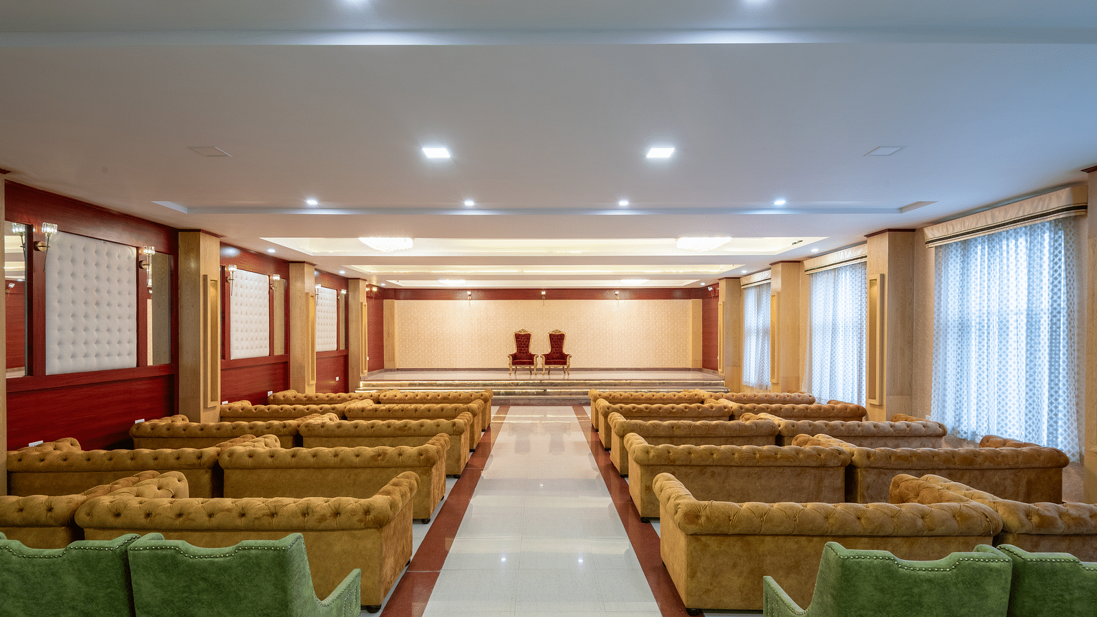 A over the shoulder shot of an expansive banquet hall with brown and green sofas at DLS Tehri Resort and Spa.